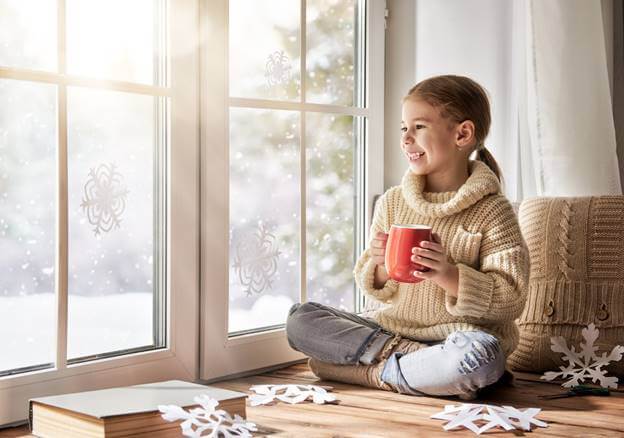 A Child Sitting By A Window in Winter