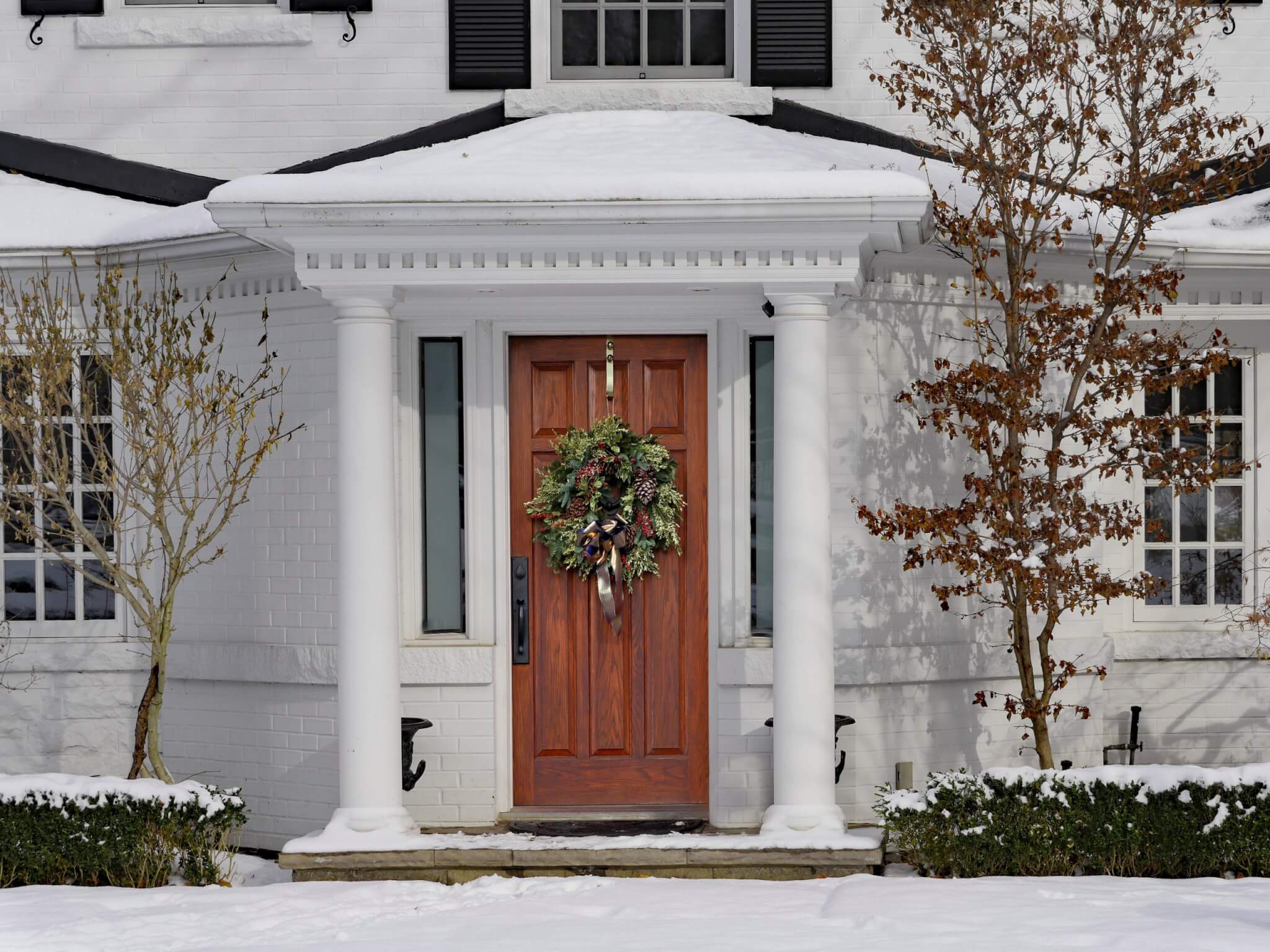 white painted house in winter with Christmas wreath