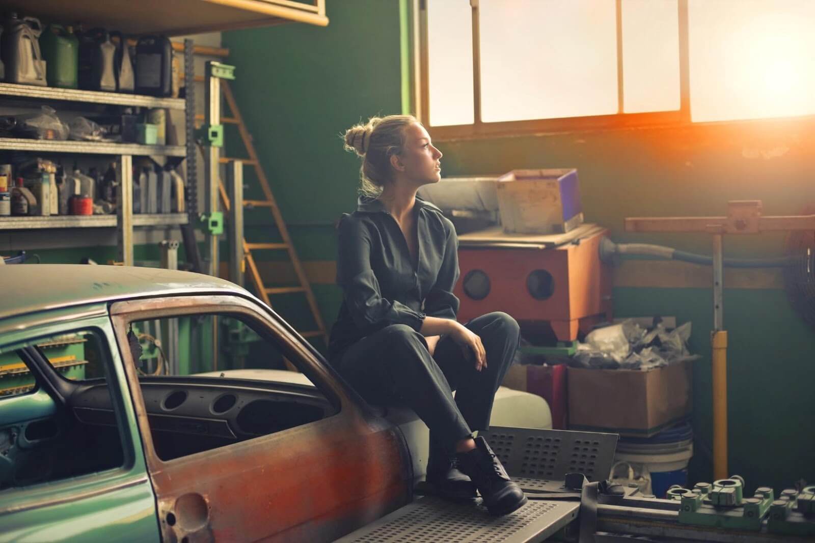 a woman sitting on top of a car in the garage