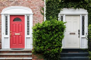 an outside view of two doors: the one on the left is red and the other on the right is white