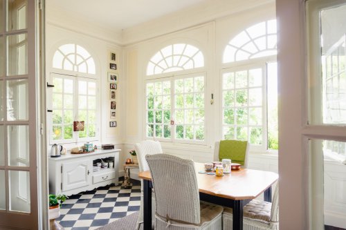 a kitchen with four chairs, a table, black and white checkered flooring and large windows