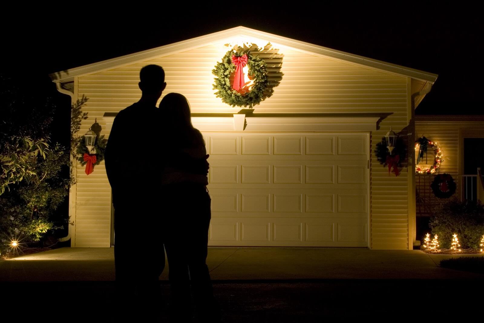 a couple admiring their garage door decorated with a wreath