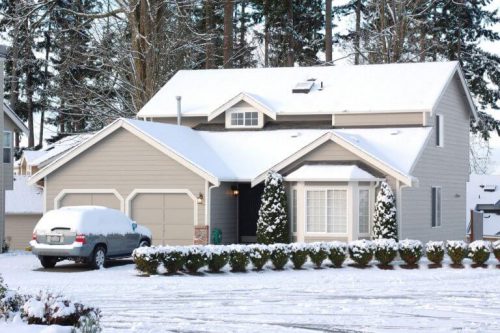 A white house with snow on the roof.