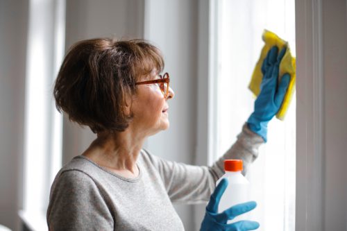 A woman cleaning a window with a yellow cloth.