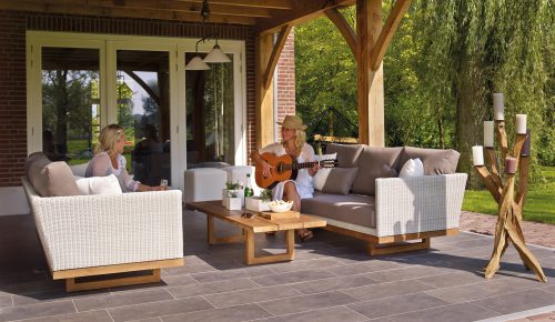 Two women are outside in the backyard patio, and one of them is playing guitar.