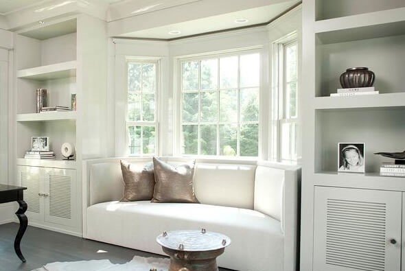A living room with a bay window and a white couch underneath it.