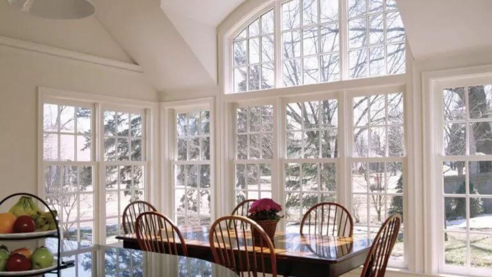 A dining room with big windows covering one wall with a dining table.