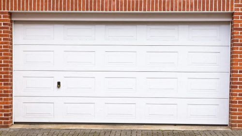 A white garage door surrounded by red brick,