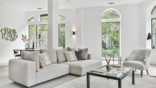A white livingroom with a white couch and gray & white chair.
