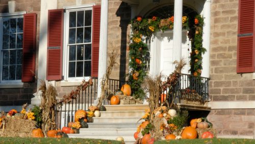 A front entrance of a home with pumpkins all around the door and down the stairs.