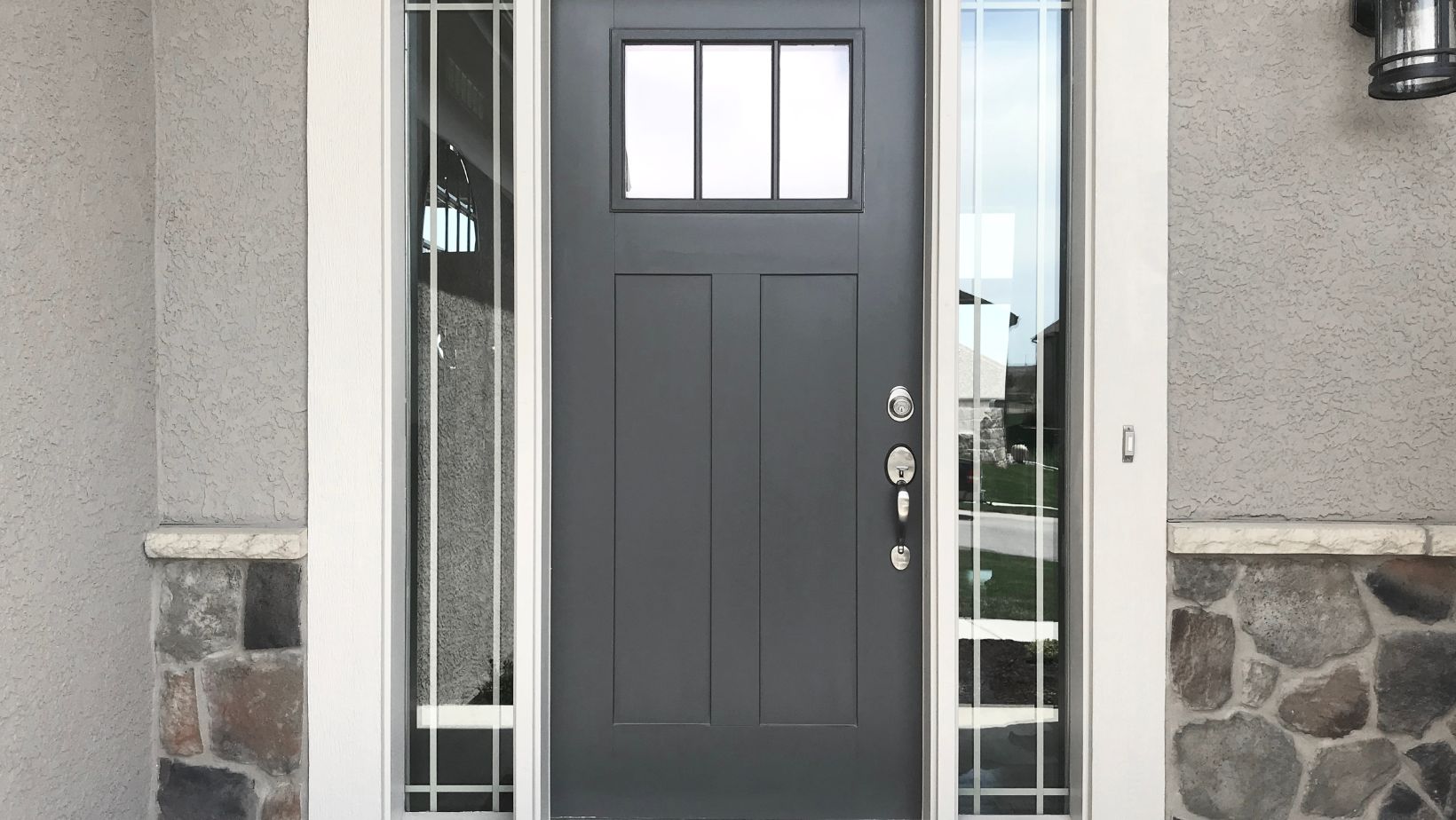 A grey front door with two long windows beside it.