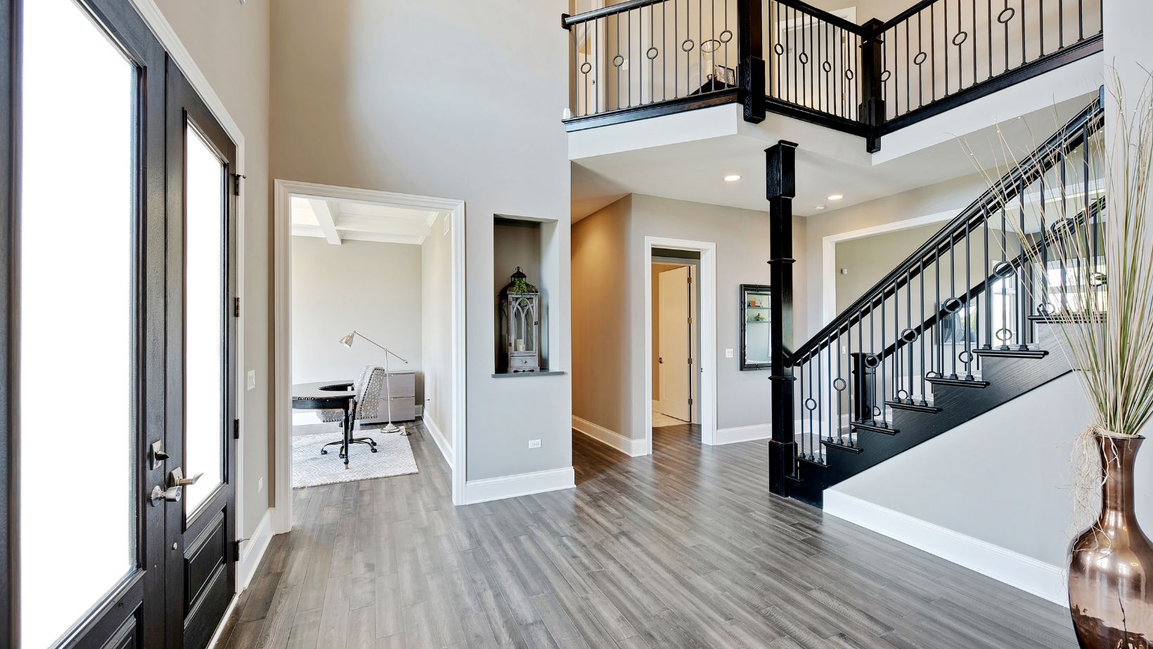 The inside front entrance of a home. With black double doors and a black stairway.