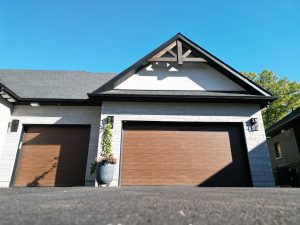 GARAGAgarage door with brown wood finish on a sunny day